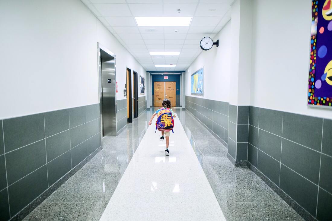 A girl running down a corridor at school, symbolizing how you can help your kids transition to a new school