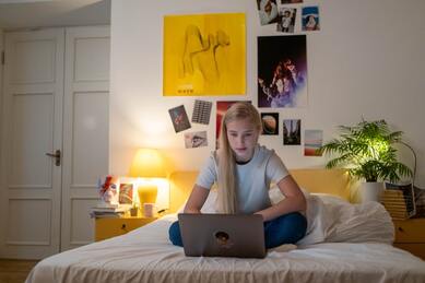 A teenage girl on her laptop in her room