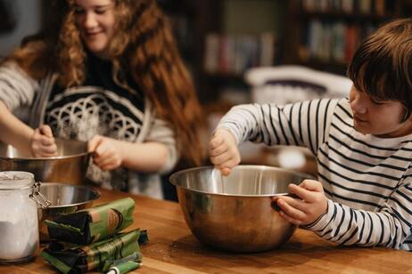  Kids mixing ingredients in a bowl to prepare dinner.