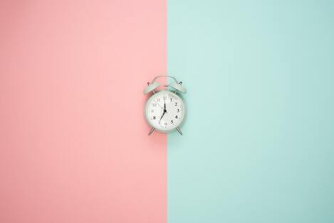 A clock on a pink and blue wallpaper